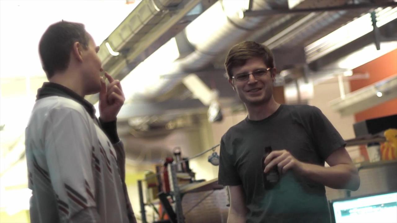 A screenshot from the documentary 'Double Fine Adventure'. Multiple game developers are having a conversating while drinking beer.